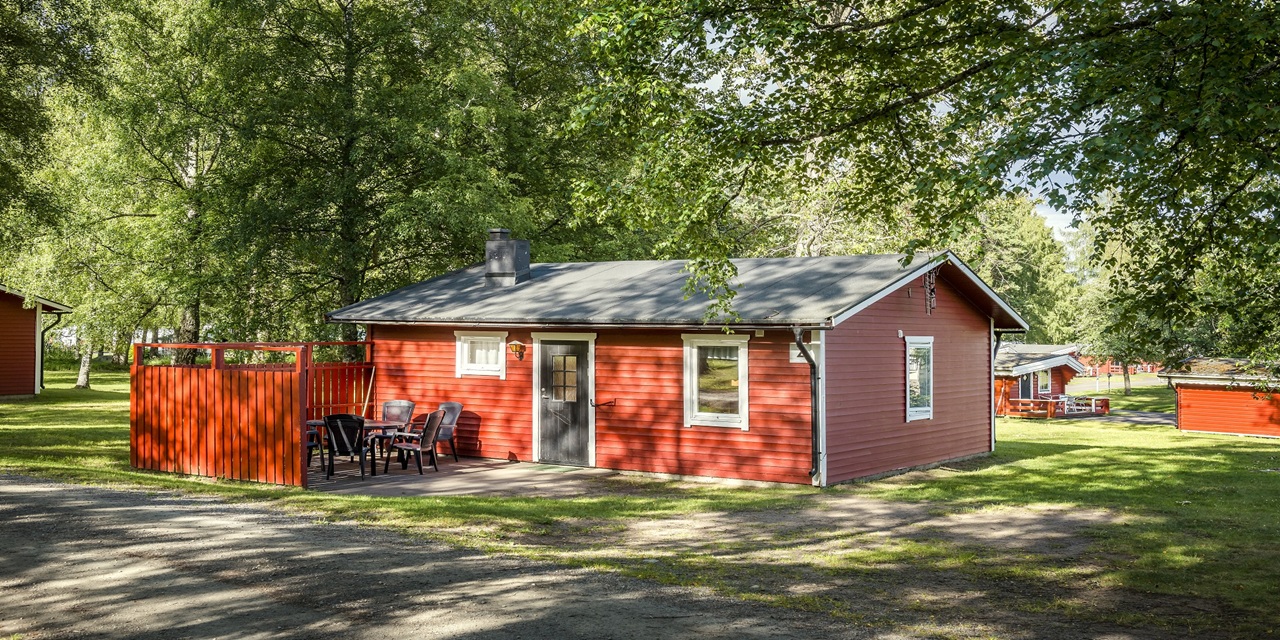 Röd trästuga med grill och utsikt i skogsmiljö